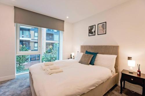 a bedroom with a large white bed and a window at Immaculate new 1 bed AC & pool Chelsea in London