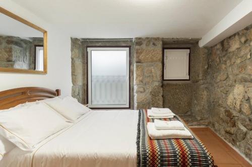 ein Schlafzimmer mit einem Bett und einer Steinmauer in der Unterkunft Rustic Getaway in Guarda in Gouveia