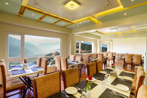 a restaurant with tables and chairs and a large window at Q SAINA MAPHAM in Darjeeling