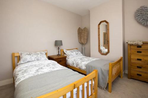 two beds in a bedroom with a mirror and a dresser at Pass the Keys Bright PetFriendly Terrace home in Stony Stratford in Stony Stratford