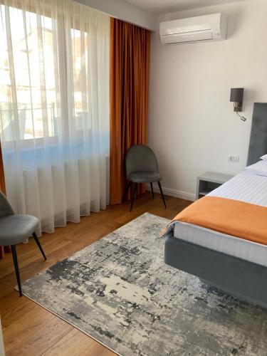 a bedroom with a bed and a chair and a window at Pensiunea Magic in Băile Govora