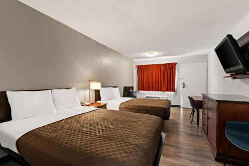 a hotel room with two beds and a flat screen tv at Rodeway Inn in Brooklawn