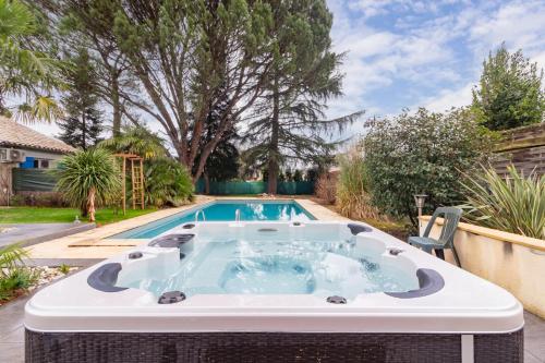 a hot tub in a backyard with a swimming pool at Chambre d'hôtes - Espaces bien-être du "Dharma Vivant" in Biars-sur-Cère