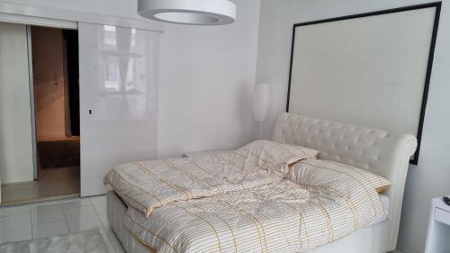ein weißes Schlafzimmer mit einem Bett mit gestreifter Decke in der Unterkunft Apartment Geibel T4 - 85m2 - Highspeed Internet - Hundefreundlich in Wien