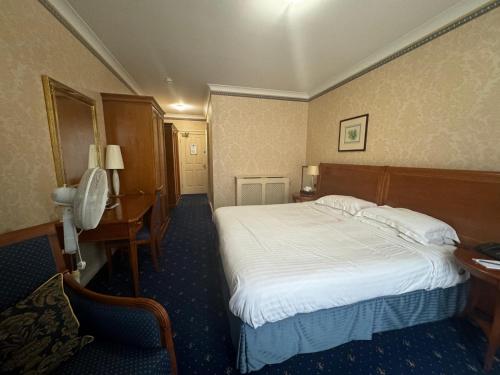 a hotel room with a bed and a desk at Tre-Ysgawen Hall & Spa in Llangefni