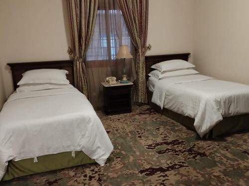 a bedroom with two beds and a table and a window at فندق روتانة الحمراء in Jeddah