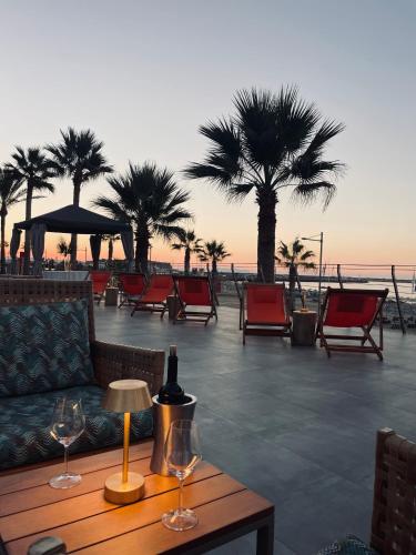 a table with wine glasses on a patio with palm trees at Aquila Porto Rethymno in Rethymno Town
