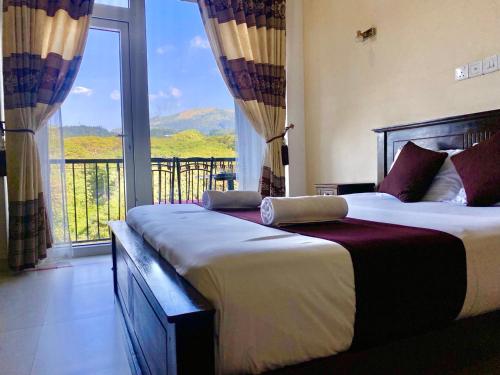 two beds in a room with a large window at Hanthana Mount View in Kandy