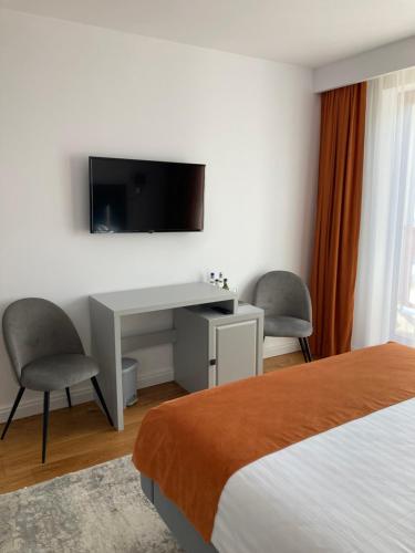 a hotel room with a desk and a tv on the wall at Pensiunea Magic in Băile Govora