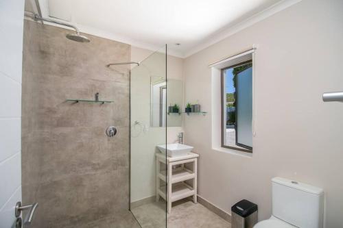 a bathroom with a shower and a toilet and a sink at Modern 1 bedroom non-seafacing unit on luxury golf estate in Knysna