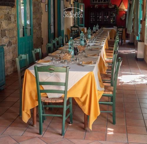 einen langen Tisch mit gelben Servietten und grünen Stühlen in der Unterkunft Hotel Sa Lolla in Barùmini