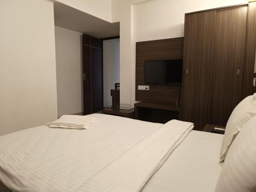 1 dormitorio con 1 cama blanca y TV de pantalla plana en Four Squares Inn, Technopark phase 3, en Trivandrum