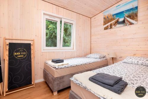 two beds in a room with wooden walls at Black Pearl in Dziwnów