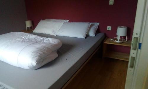uma cama com lençóis brancos e almofadas num quarto em Chalets à 10 minutes de Foix em Mercus-Garrabet