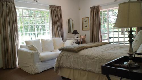 een slaapkamer met een bed, een stoel en een raam bij klipspruit oudekraal farmhouse in Dullstroom