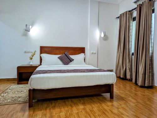een slaapkamer met een groot bed met een houten hoofdeinde bij Les Ombrelles Appart'Hotel in Cotonou
