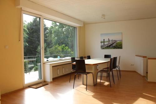 een eetkamer met een tafel en stoelen en een groot raam bij Mont Apartments in Erkrath