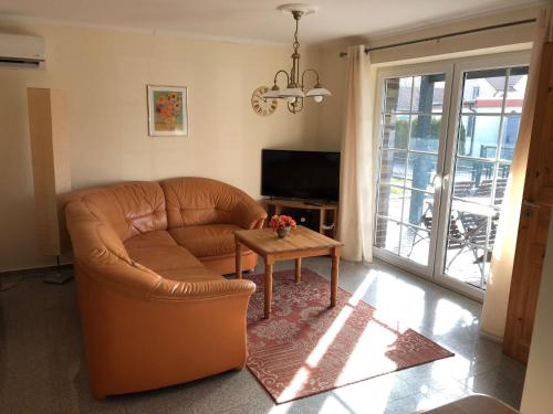 a living room with a leather couch and a table at Haus-Koralle-Wohnung-links in Boltenhagen