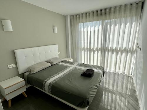 a bedroom with a bed and a large window at PISO-DEL-PLAYA in Guardamar del Segura