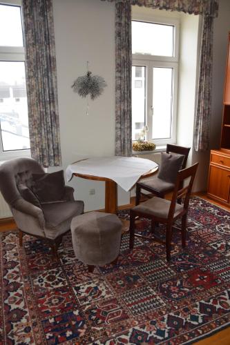 ein Wohnzimmer mit einem Tisch, Stühlen und einem Teppich in der Unterkunft Garconniere im ehemaligen Hotel Austria in Gmunden