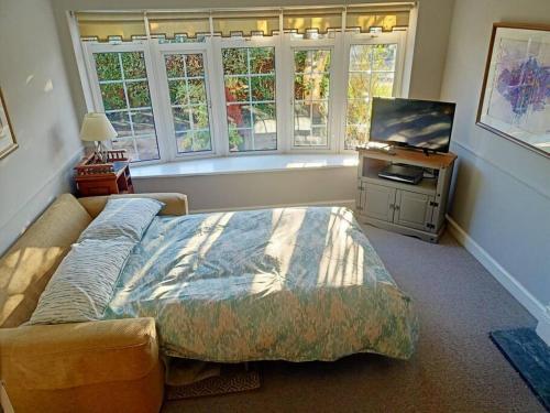 a bedroom with a bed and a flat screen tv at Lotus House in Needingworth