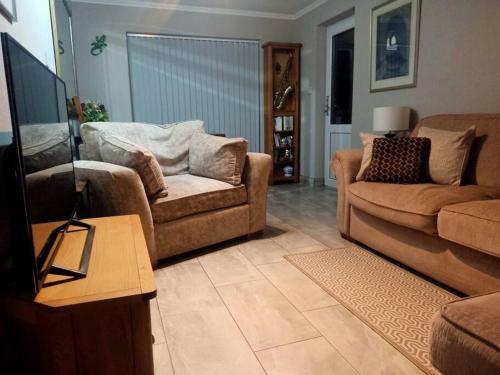 sala de estar con 2 sofás y TV de pantalla plana en Lotus House, en Needingworth
