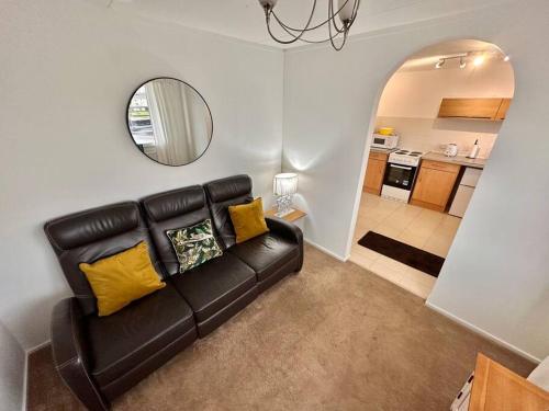 a black leather couch in a living room with a mirror at Semi-detached 1-Bedroom Chalet in Uddingston