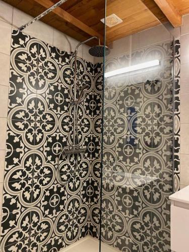 une douche dans une salle de bain avec un motif noir et blanc dans l'établissement U Sortipiani, à Sortipiani