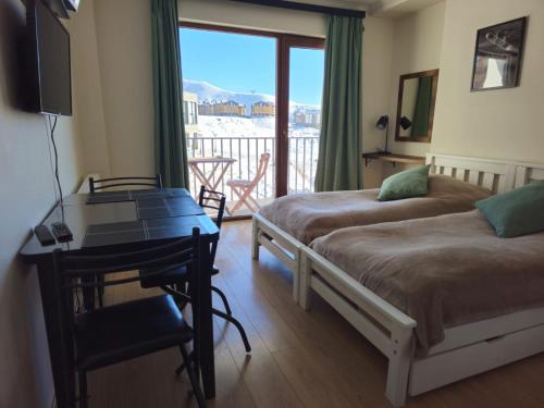 a bedroom with two beds and a desk and a balcony at Gudauri Vista 6 in Gudauri