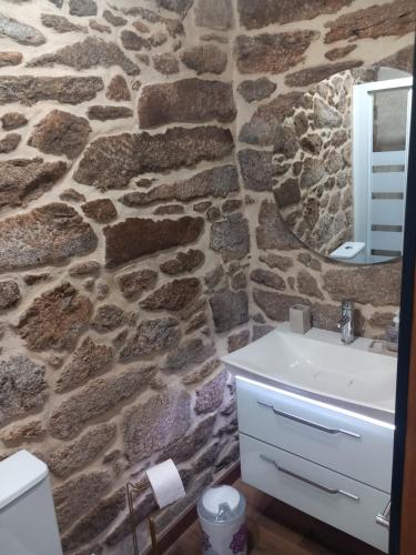 Baño de piedra con lavabo y espejo en Casa de Crabera, en A Coruña