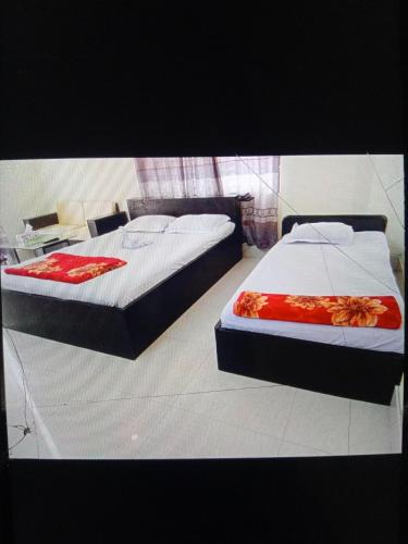 dwa łóżka siedzące obok siebie w sypialni w obiekcie Rose Garden Guest House w mieście Khulna