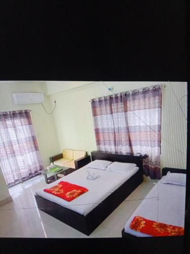 a bedroom with a bed and two windows at Rose Garden Guest House in Khulna