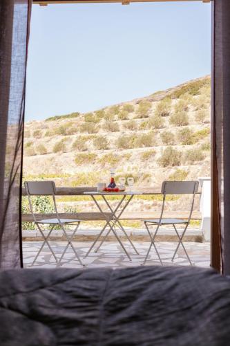 a table and two chairs in a room with a view at Mikra Bay Vineyard Guesthouses in Naxos Chora