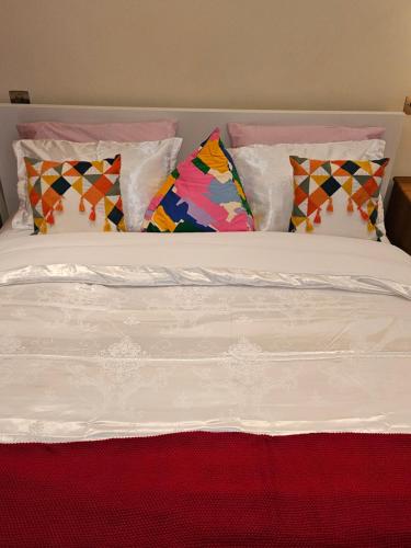 a white bed with colorful pillows on it at LONDON HEATHROW GLAMOUR MANSION HOUSE in Uxbridge