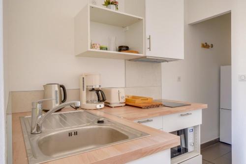 - une cuisine avec un évier et des placards blancs dans l'établissement Jolie petite maison de ville Bordeaux, à Bordeaux