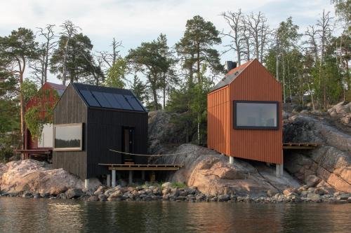 two houses on the shore of a body of water at Majamaja Helsinki off-grid retreat in Helsinki