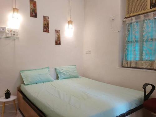 a small bedroom with a bed with white sheets and blue pillows at A rustic earthy home A1 in Mumbai