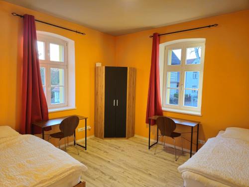 a bedroom with two beds and two desks and two windows at Ferienwohnung Gebauer in Görlitz