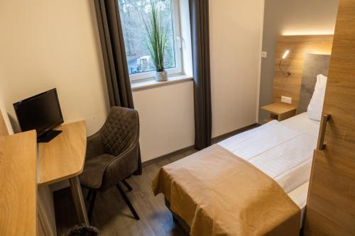 a hotel room with a bed and a desk and a window at Balkes Morhoff in Petershagen