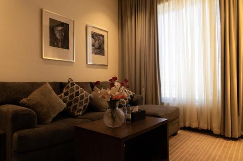 a living room with a couch and a table with flowers at Dream Residence Olaya Khobar in Al Khobar