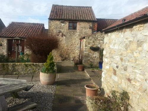 un edificio in pietra con panchina e piante in un cortile di The Castle Arms Inn a Bedale