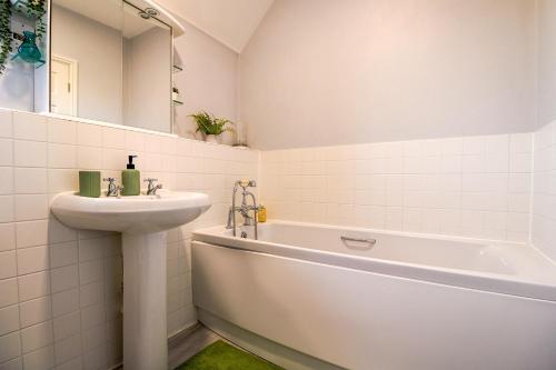 y baño blanco con lavabo y bañera. en Stylish 2 Bedroom Maisonette in Hatfield by HP Accommodation en Hatfield