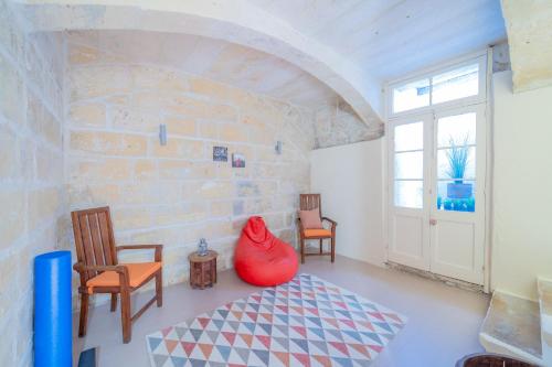 une chambre avec deux chaises et un vase rouge dans l'établissement Typical Maltese town house just outside Valletta, à Il-Furjana
