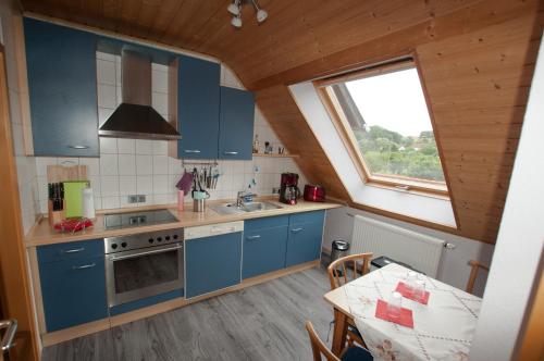 eine Küche mit blauen Schränken, einem Tisch und einem Fenster in der Unterkunft Business Apartment in Glanbrücken