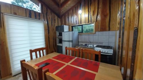 a kitchen with a wooden table and a refrigerator at Cabañas la Estrella in Neltume