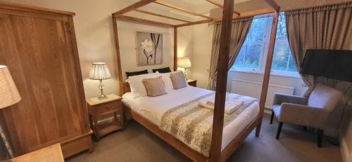 a bedroom with a bed and a chair and a window at Woodlands in Windermere