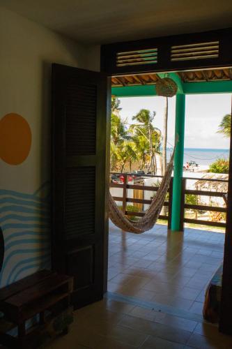 a room with a hammock and a view of the beach at Indiana Kite school and Hostel in Cumbuco