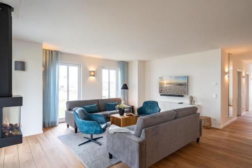 ein Wohnzimmer mit einem Sofa, Stühlen und einem Kamin in der Unterkunft Domizil Meerzeit, App. 7 in Ahlbeck