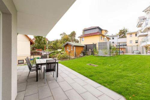 een patio met een tafel en stoelen in een tuin bij Domizil Meerzeit App 6 in Ahlbeck