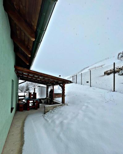 een gebouw met sneeuw op de grond naast een hek bij Cabana Bilbor in Bilbor